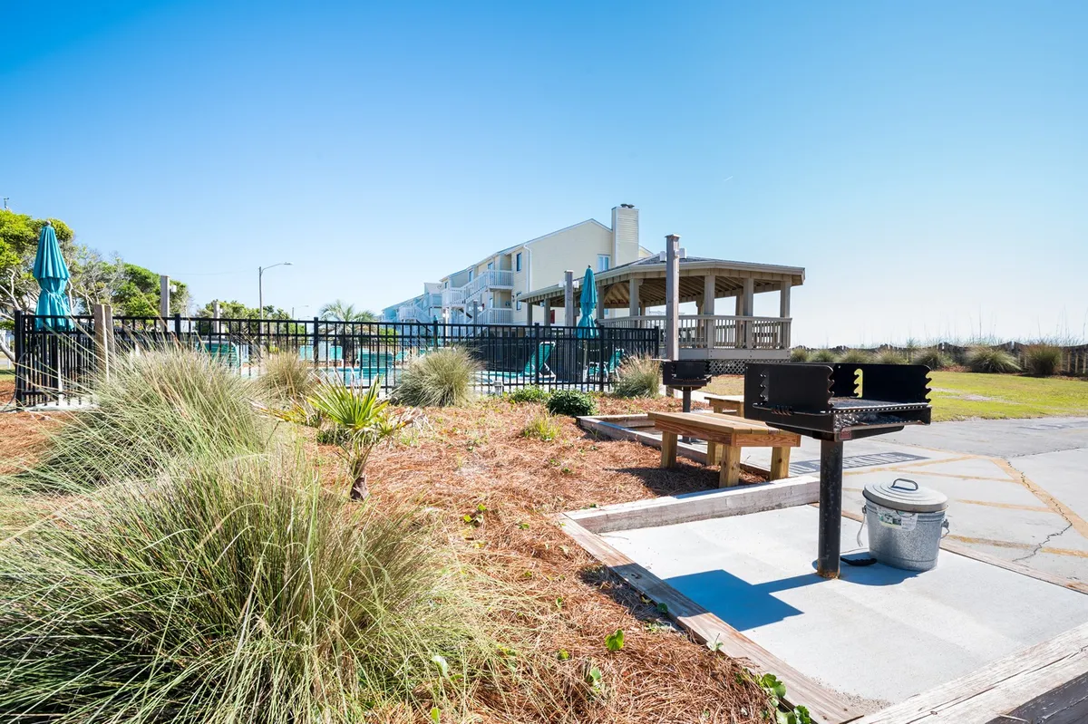 This image features a grill area with a picnic table, swimming pool views, and lush landscape vegetation. It evokes casual gatherings, barbecues, and relaxed outdoor dining by the pool, making it perfect for family meals after a day of adventure.