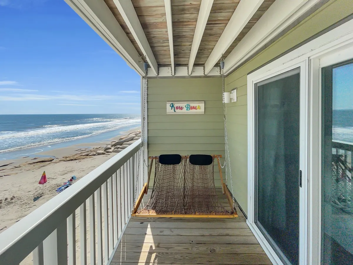 A tranquil hammock is stretched between deck posts, with a clear view of the sandy beach and ocean beyond. The area exudes relaxation and invites you to gently sway while enjoying the sound and sight of the waves.
