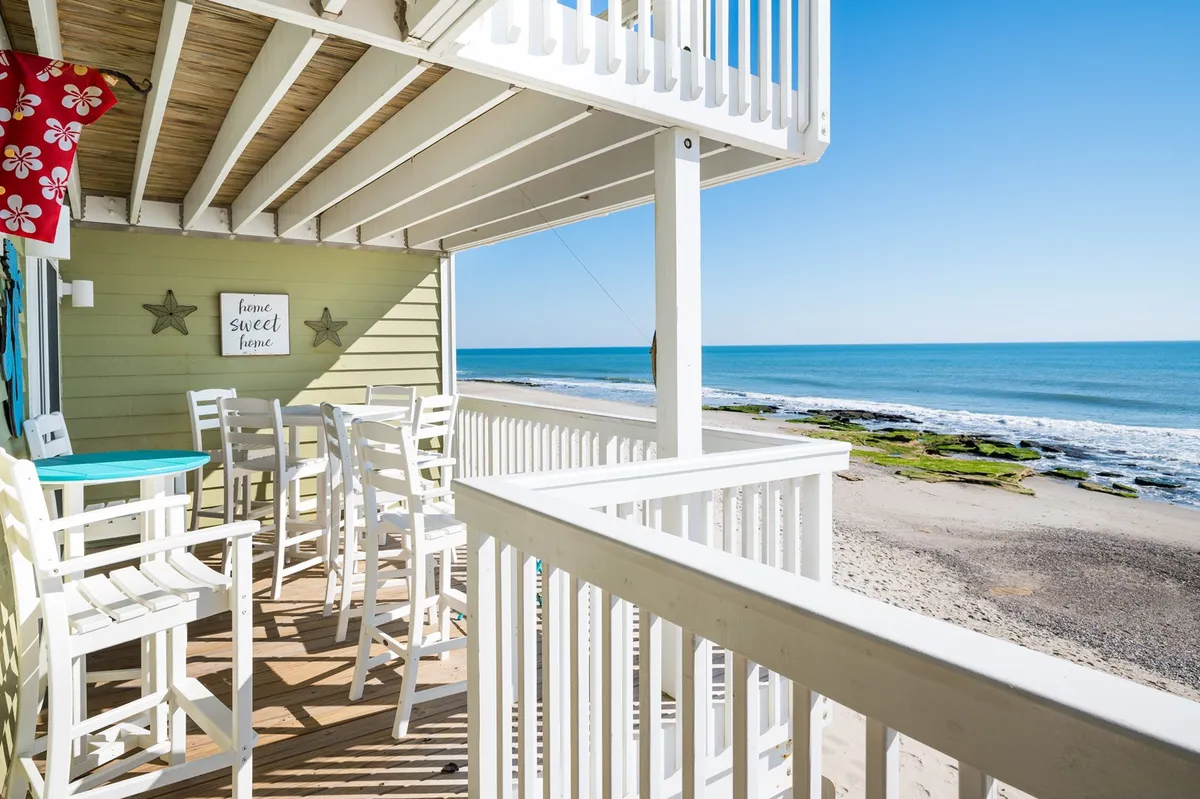 An inviting outdoor seating area arranged to maximize the sweeping ocean view. Decorative accents and comfortable furnishings create a welcoming atmosphere for morning coffee, sunset cocktails, or simply lounging while watching the waves.